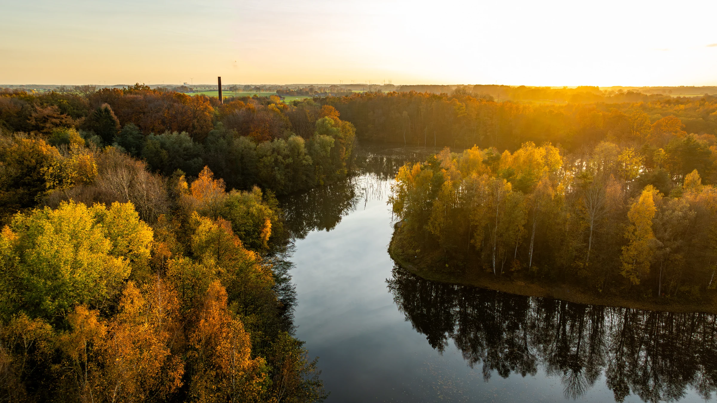 Drohnenaufnahme eines Sees in herbstlicher Landschaft