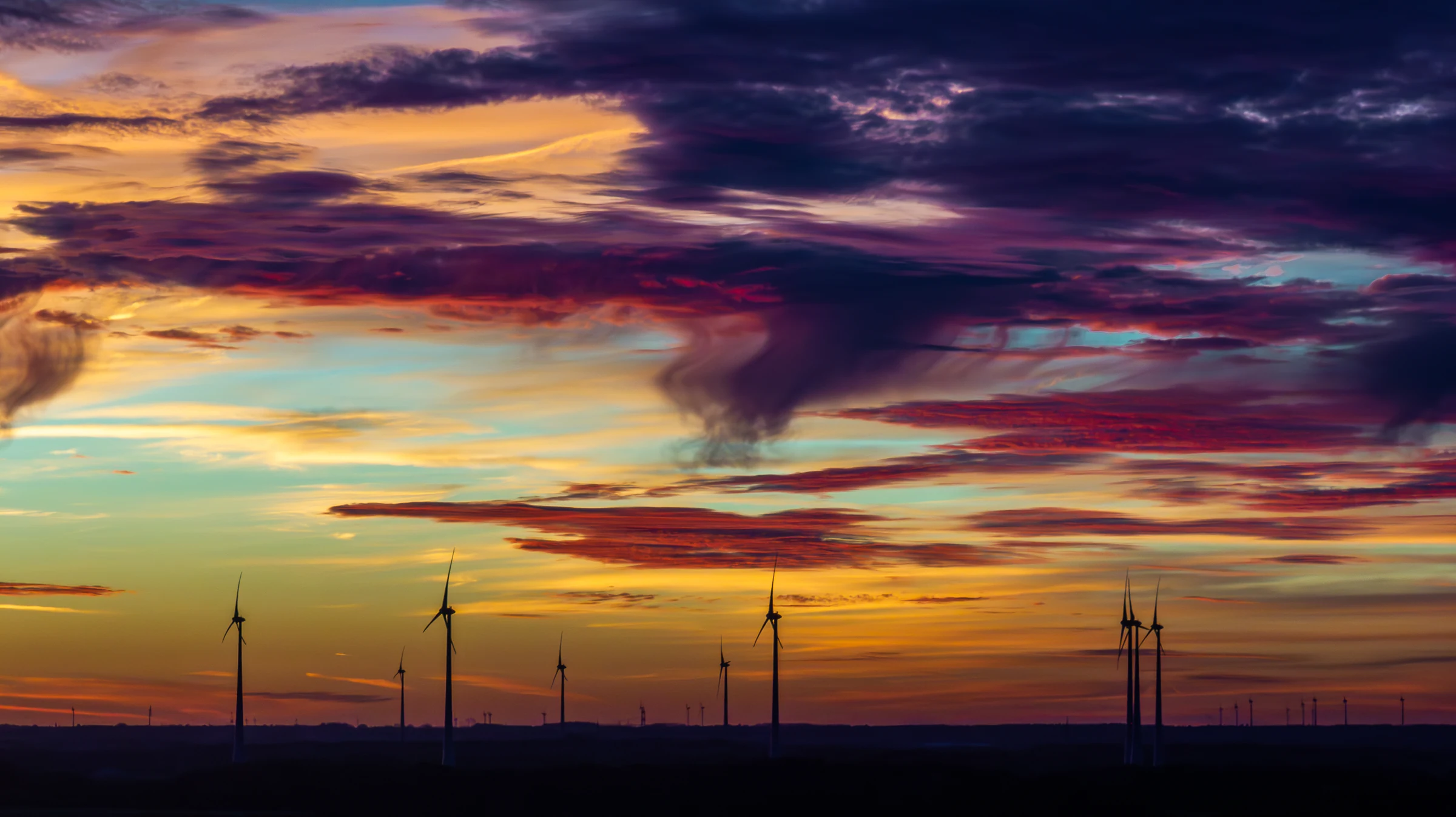 Windkraftanlagen unter einem farbintensiven Abendhimmel